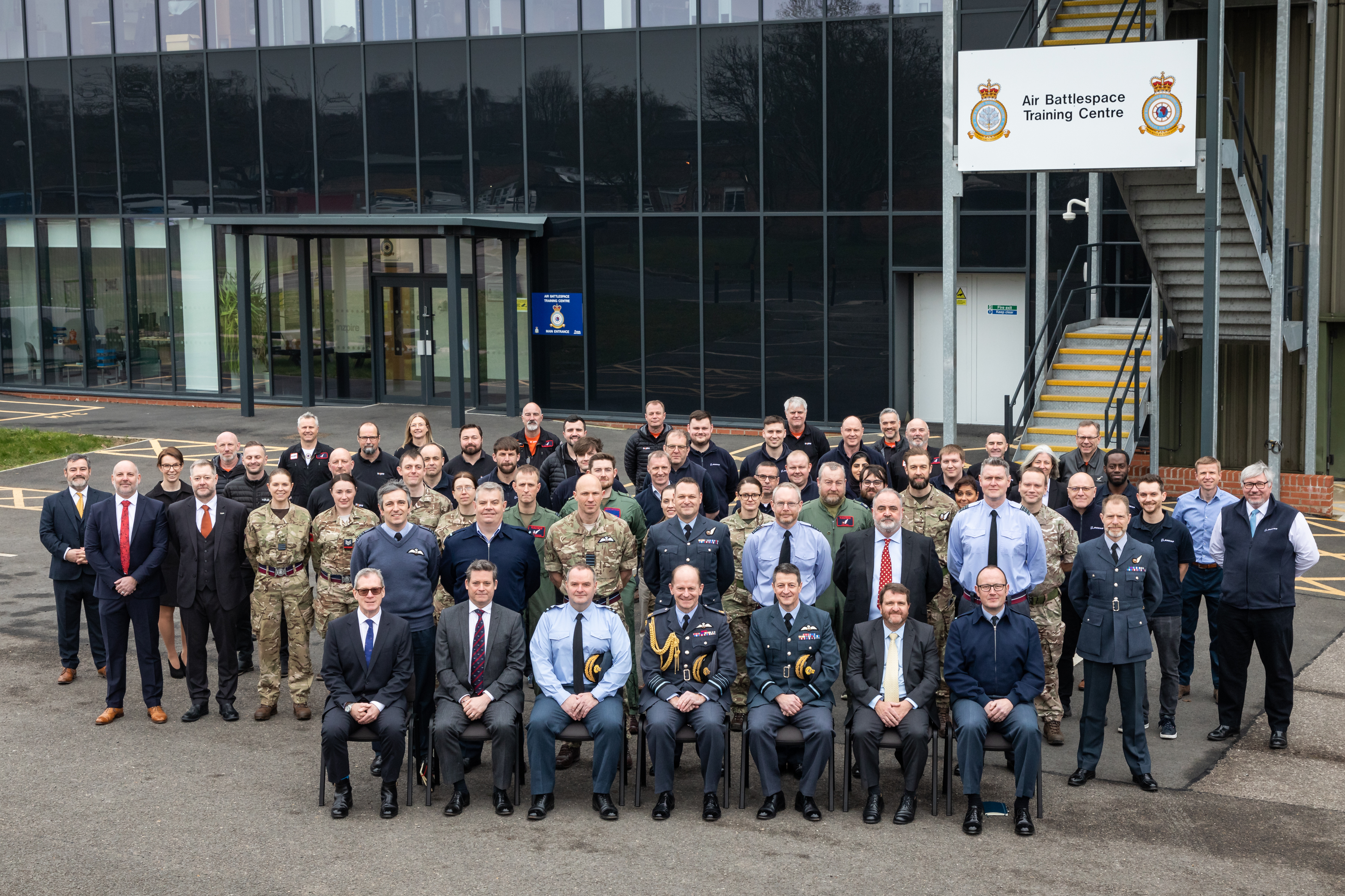 Image show RAF aviators and civilians in group photo outside Air Battlespace Training Centre.